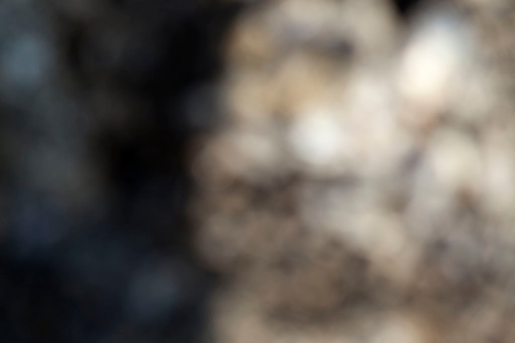 Depoe Bay, OR 2017 — dark and warm stone abstract with deep shadow left and blurred pebbles right