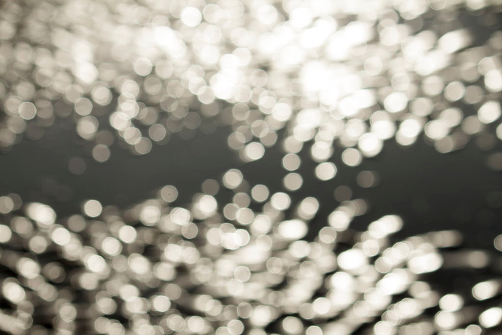 Depoe Bay, OR 2017 — silver bokeh water reflections, dense circular light orbs on dark grey