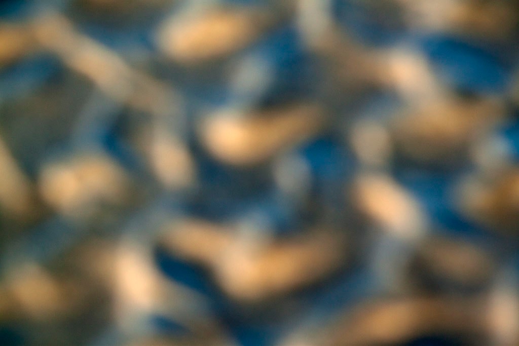 Depoe Bay, OR 2017 — blurred underwater stones abstract, warm golden tan forms on deep blue ground