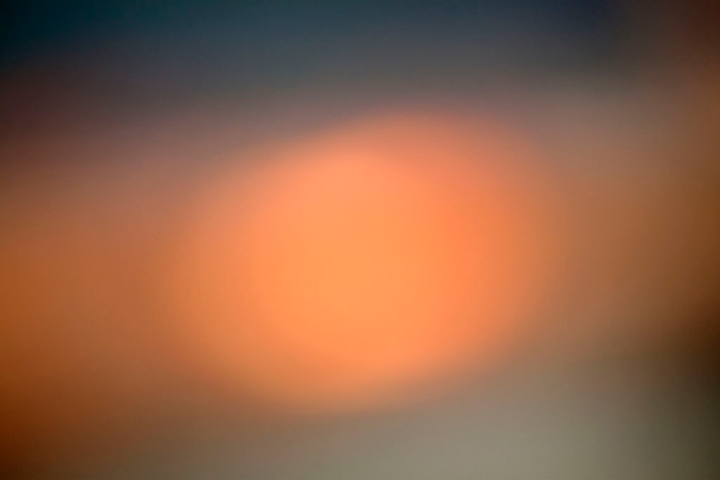 Depoe Bay, OR 2017 — soft sunset abstract, warm peach-orange glow centered on cool dark grey-blue ground