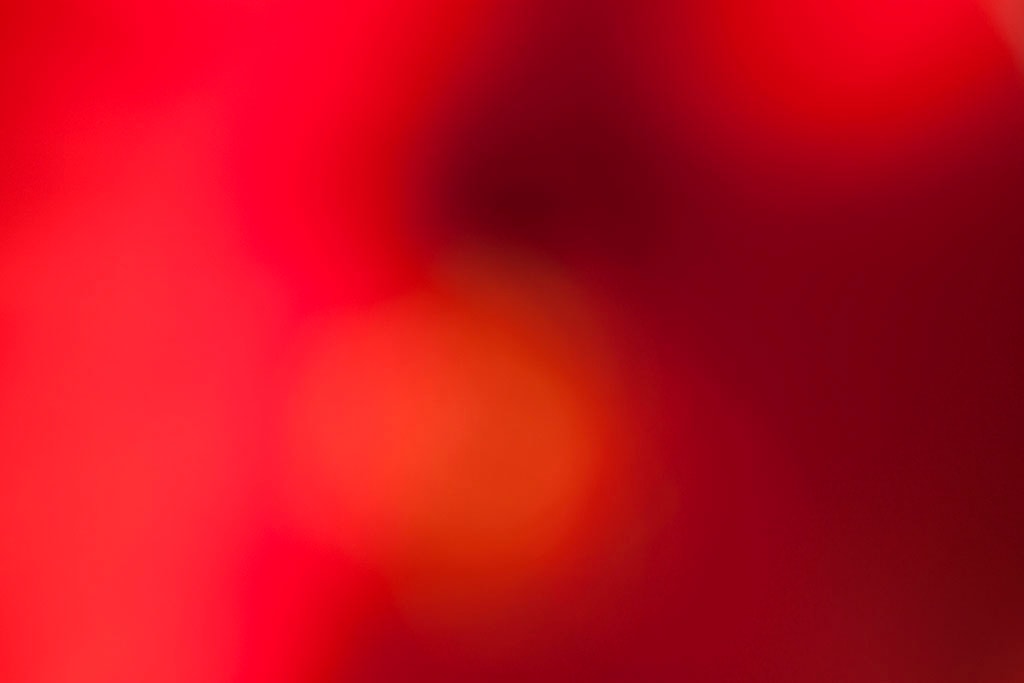 Maui, Hawaii 2018 — vivid red bokeh abstract, warm orange glowing orb center-left on deep crimson and dark burgundy ground